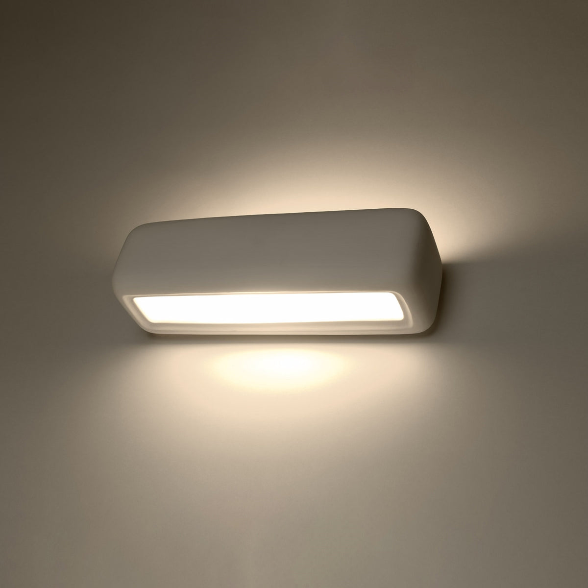 Applique allumée fixée au mur, diffuse une lumière chaude vers le haut et le bas.