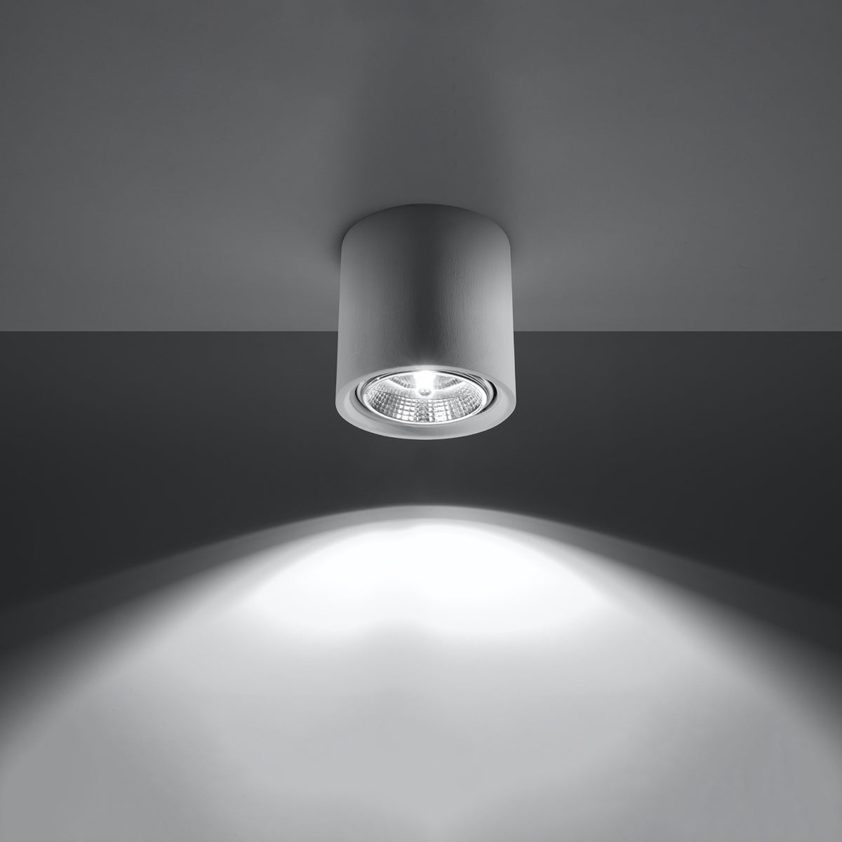Luminaire allumé projetant un large faisceau lumineux blanc sur une surface sombre