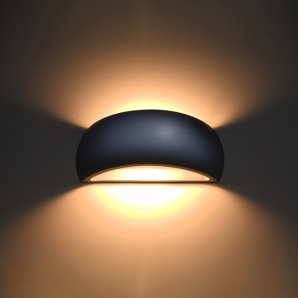 Version noire de l'applique allumée, diffuse lumière chaude en haut et en bas.