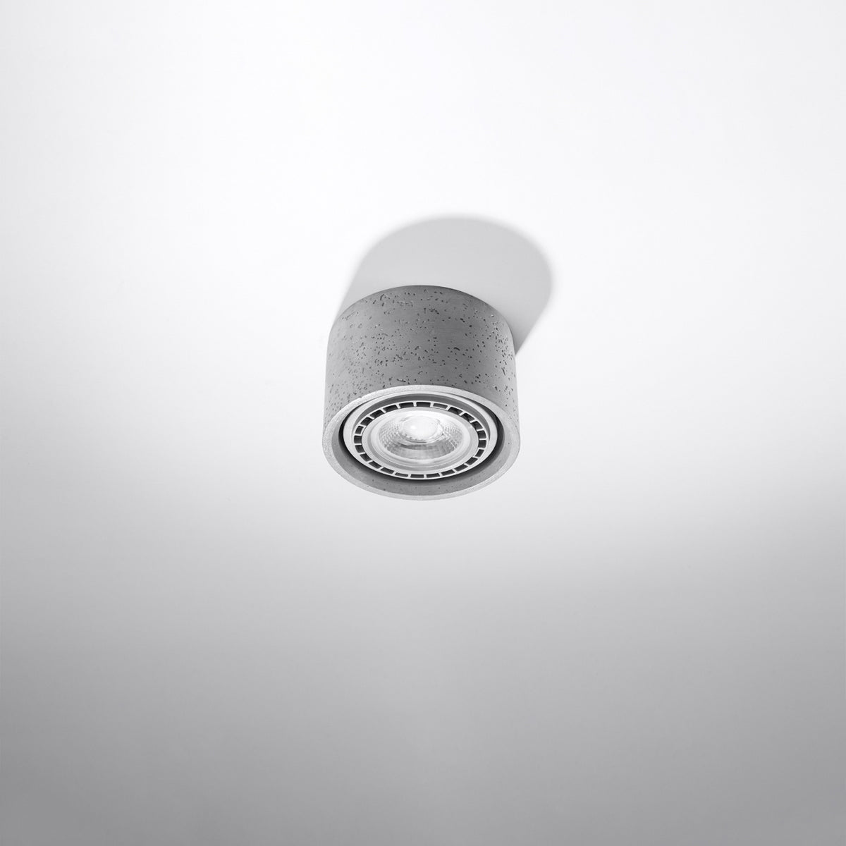 Vue en contre-plongée du luminaire montrant la texture brute du béton et le réflecteur.