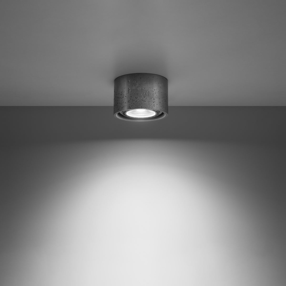 Mise en ambiance du plafonnier allumé dans une pièce sombre avec halo lumineux mural.