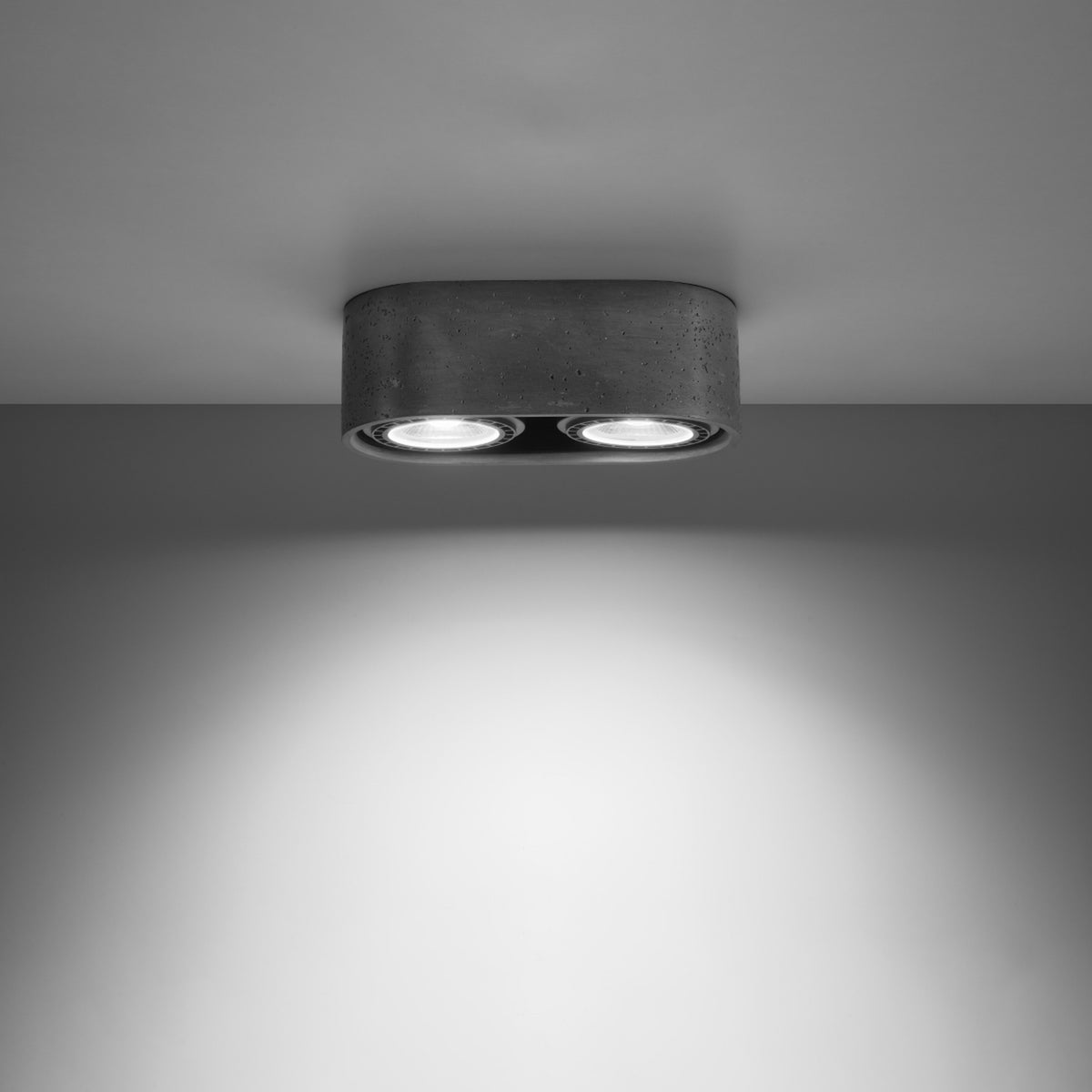 Plafonnier allumé fixé au plafond, éclairant un mur gris.