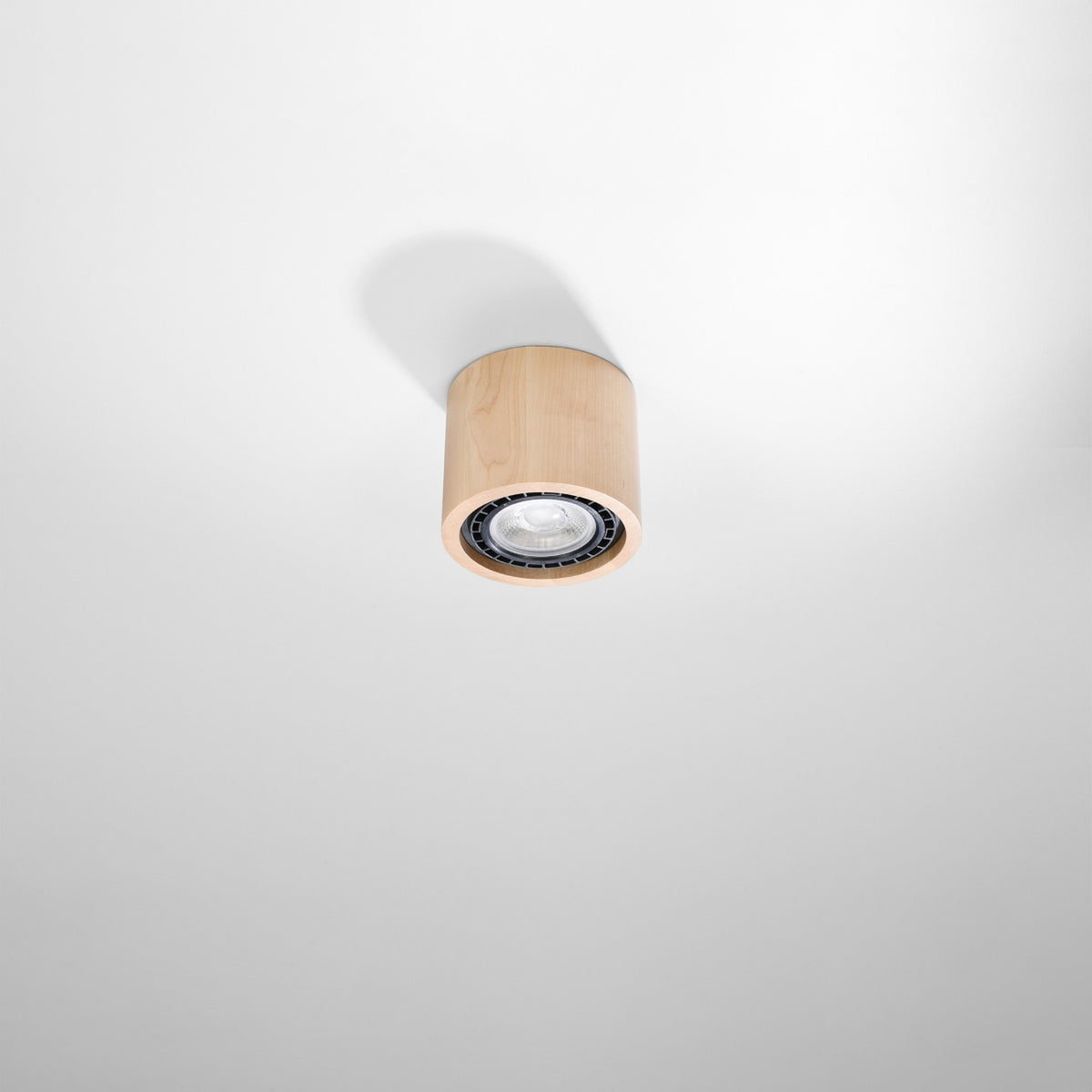Plafonnier cylindrique en bois vu en contre-plongée, fixé sur un plafond blanc