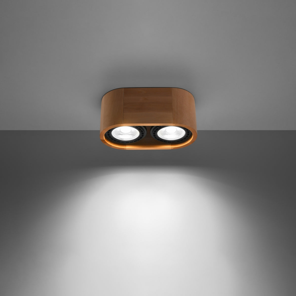 Luminaire allumé sous plafond gris, faisceau lumineux descendant des deux spots