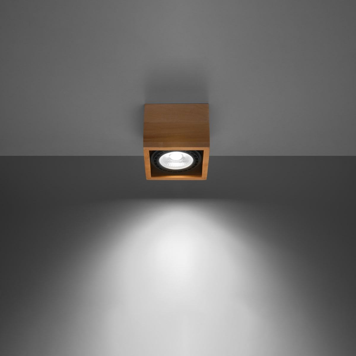 Plafonnier en bois allumé au plafond gris, diffusant un faisceau lumineux vers le bas.