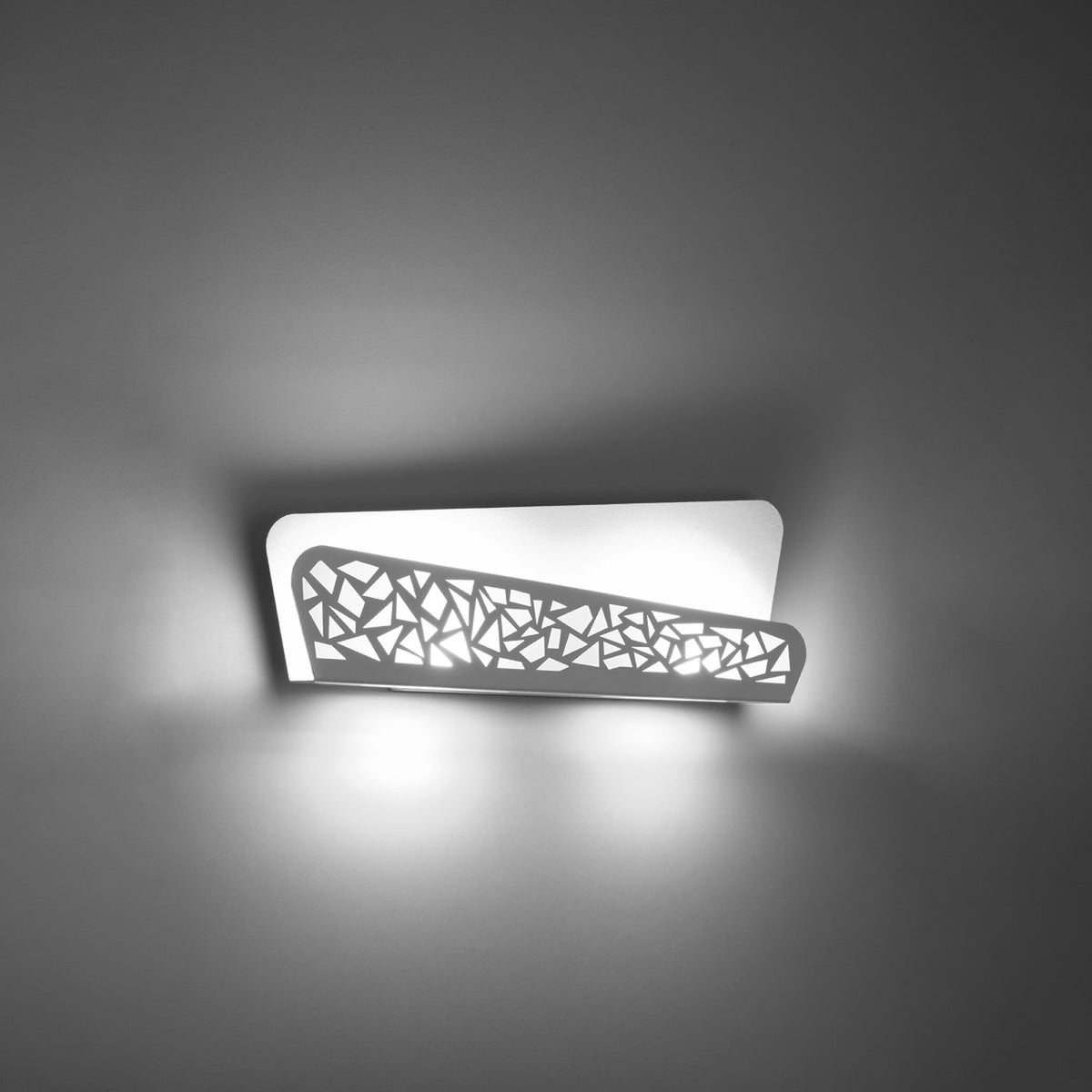 Applique allumée diffusant une lumière vive à travers les découpes de l'abat-jour.