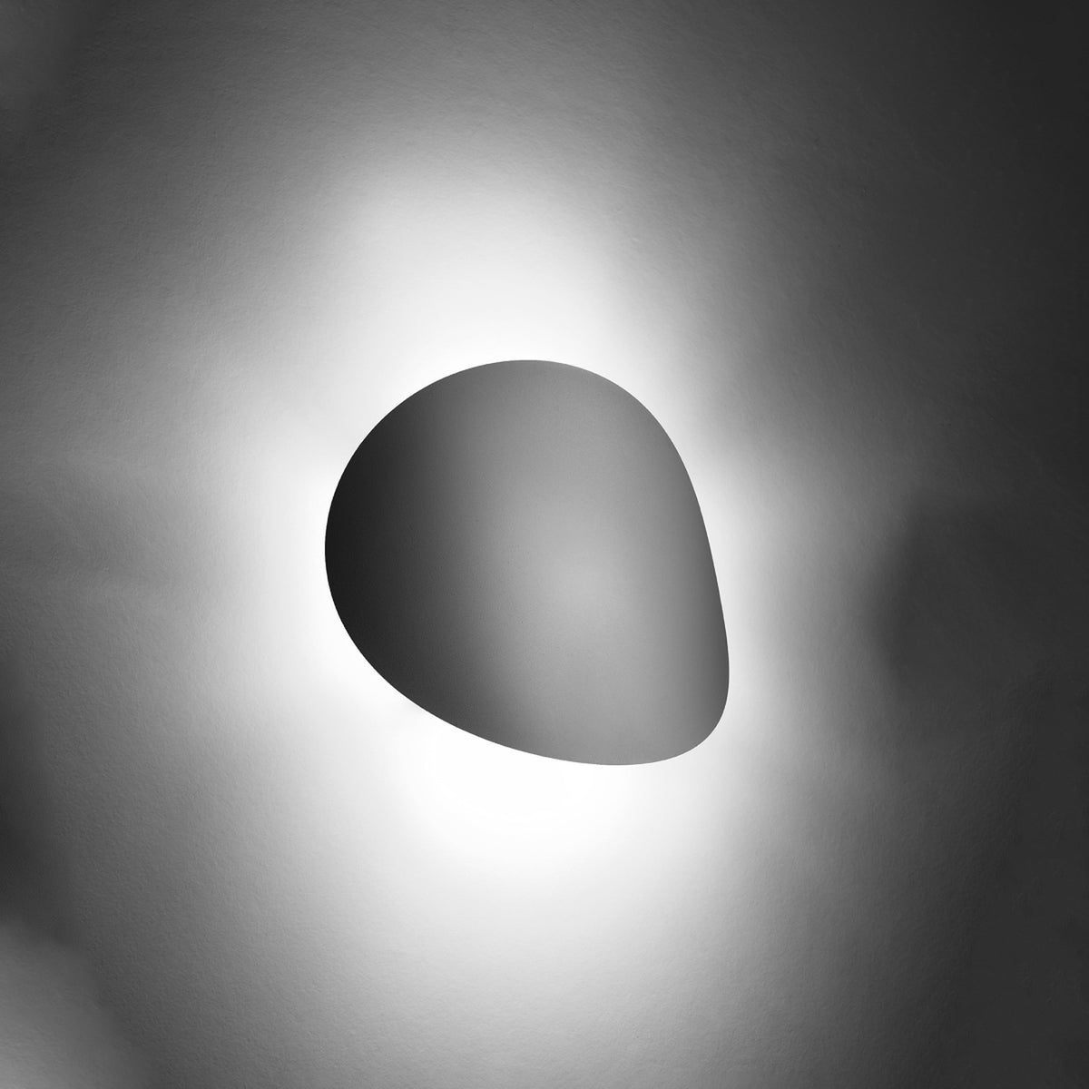Vue de nuit, halo lumineux diffus autour du diffuseur mural blanc en ambiance sombre.