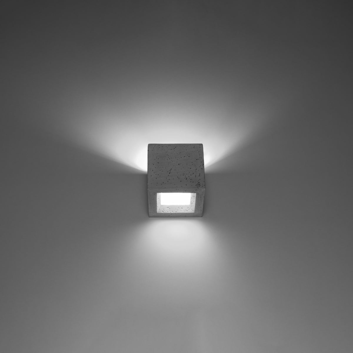 Applique murale allumée sur un mur, halo lumineux diffusé vers le haut et le bas.