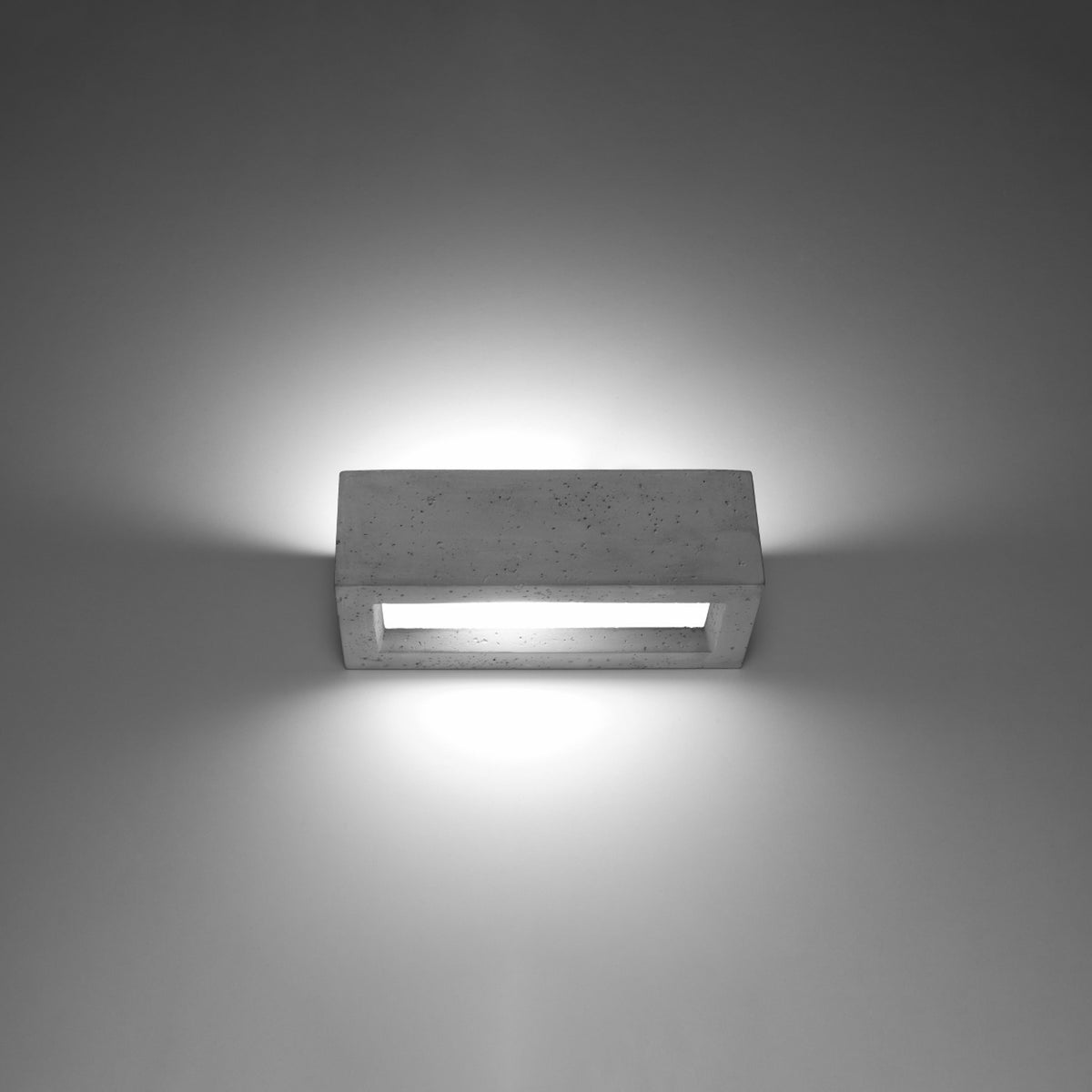Applique allumée sur mur gris, halo de lumière vers le haut et le bas