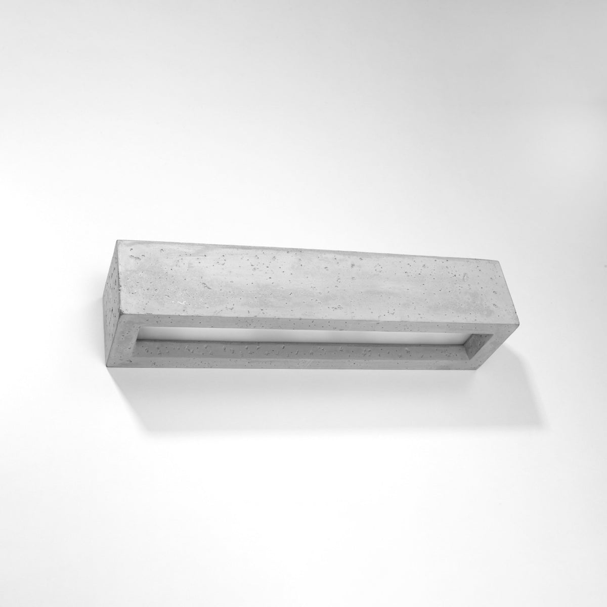 Vue de trois quarts du luminaire en béton texturé posé sur fond blanc neutre.