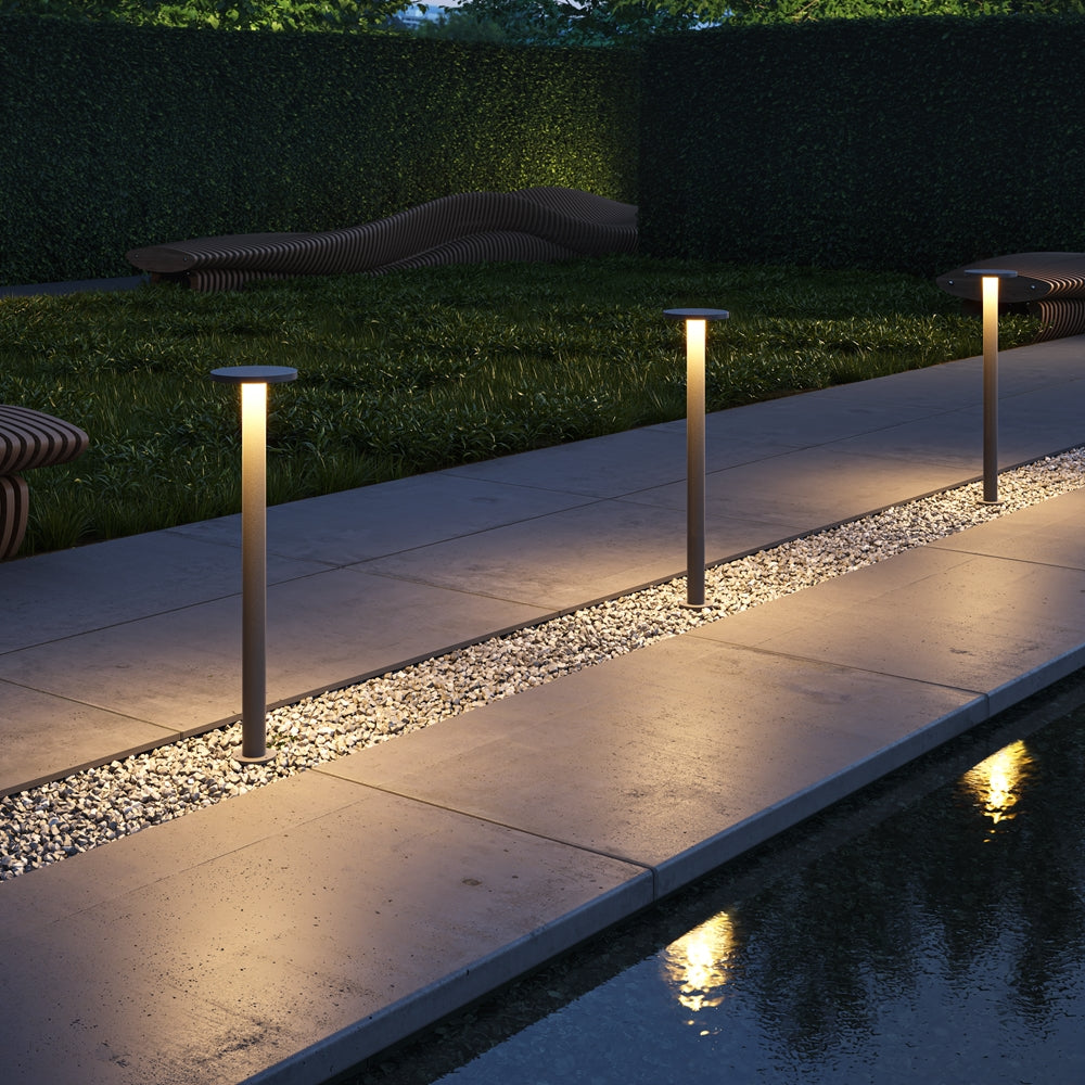 Mise en ambiance nocturne, trois bornes lumineuses alignées le long d'une allée
