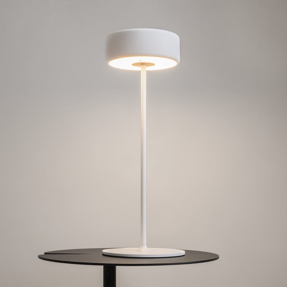 Lampe allumée posée sur une table ronde noire, halo lumineux chaud