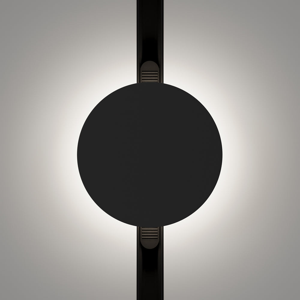 Face avant du disque noir sur rail, halo lumineux diffus projeté sur le mur