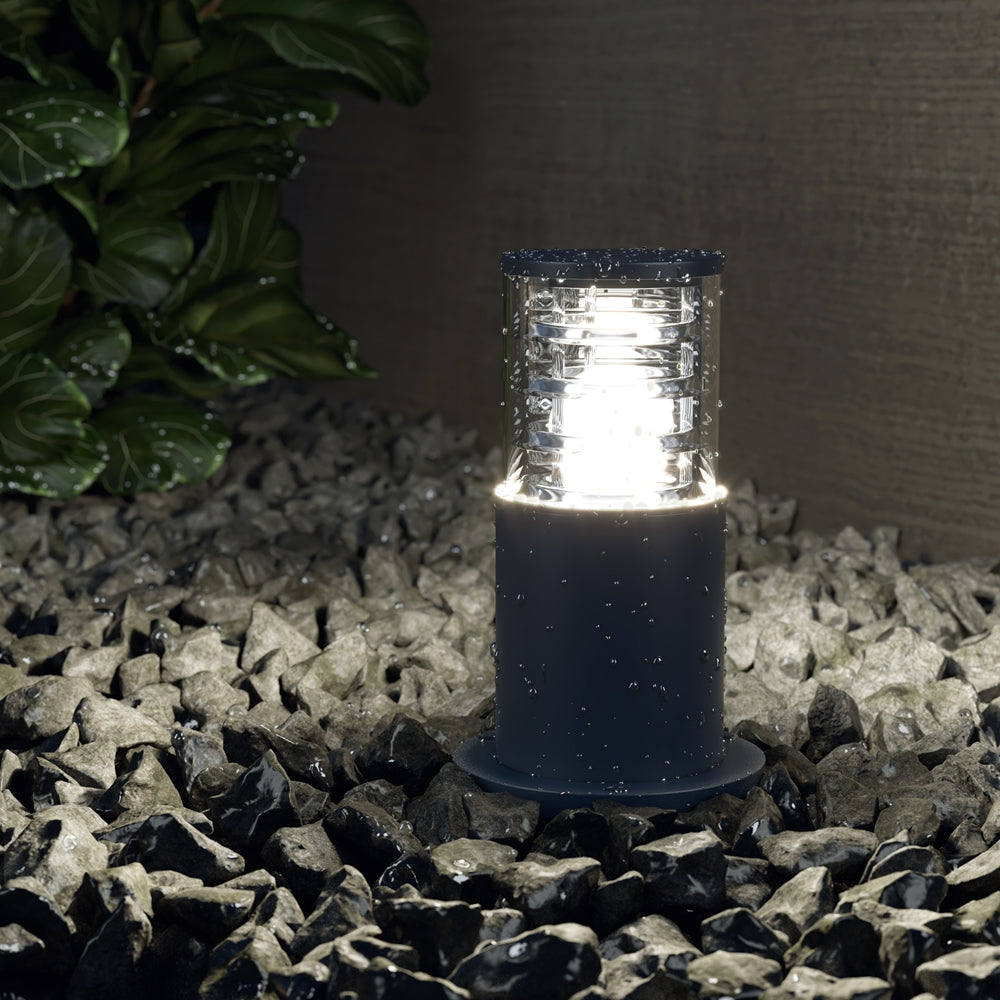 Mise en ambiance nocturne du luminaire allumé posé sur gravier près d'une plante