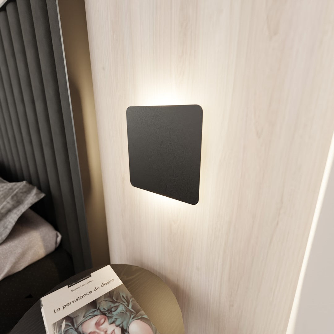 Applique allumée fixée sur une tête de lit en bois clair, lumière rasante