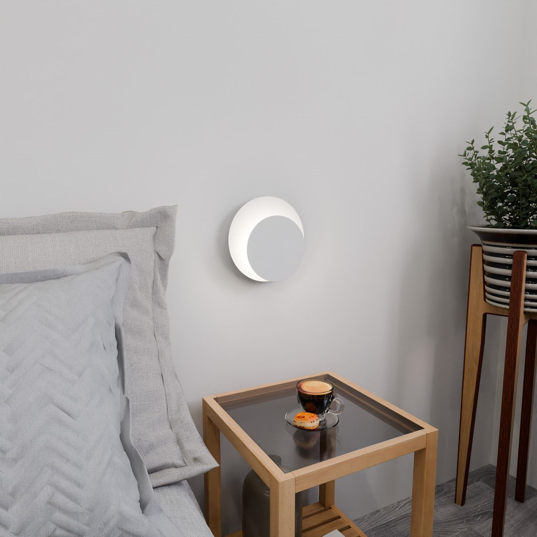 Applique murale allumée au-dessus d'une table basse, tasse de café et coussins dans chambre.