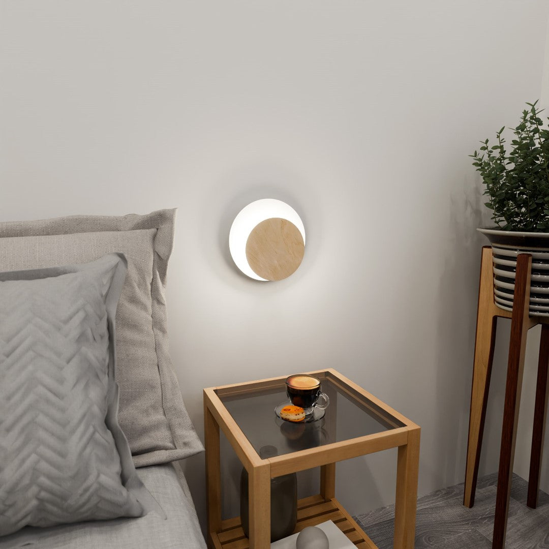 Applique allumée au-dessus d'une table de chevet, halo lumineux doux dans la chambre.