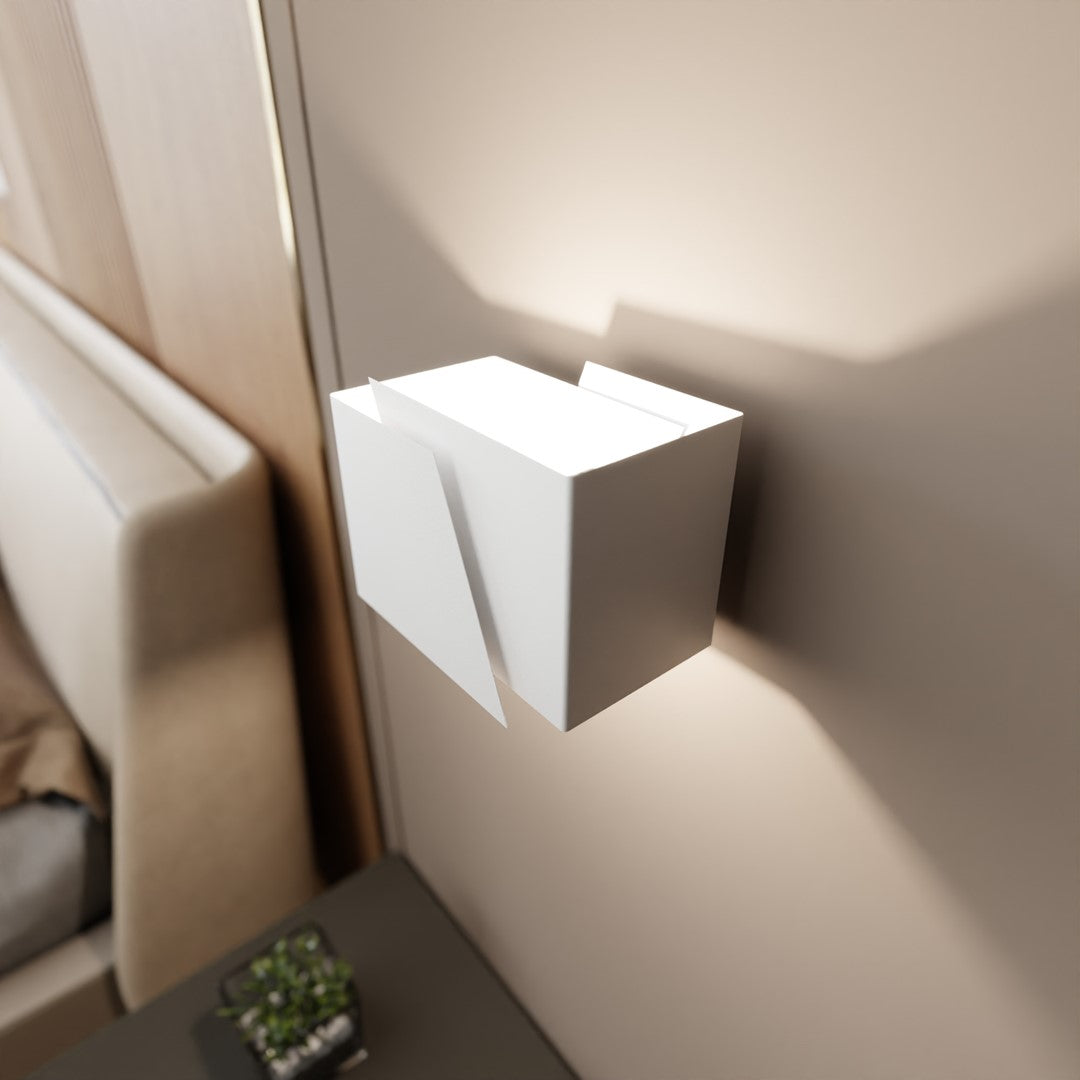 Applique murale blanche allumée dans une chambre, près du lit et table de nuit.