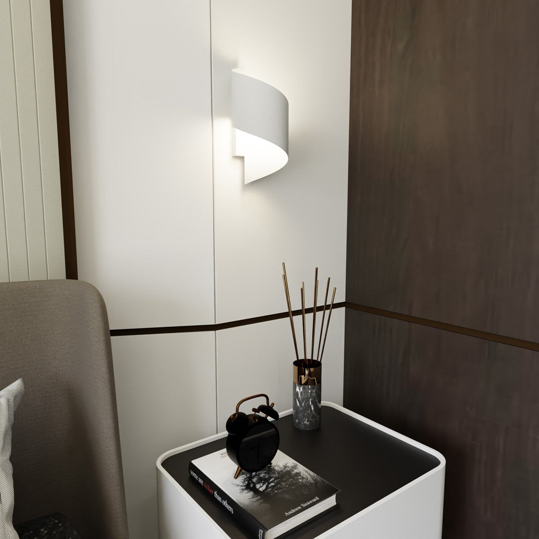 Applique murale blanche allumée au-dessus d'une table de chevet avec livre et diffuseur.