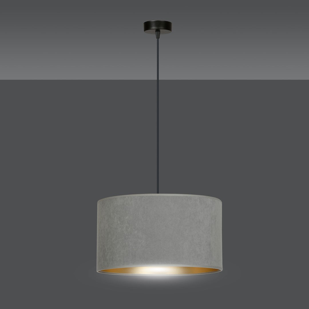 Suspension allumée, halo lumineux doré projeté sous l'abat-jour cylindrique