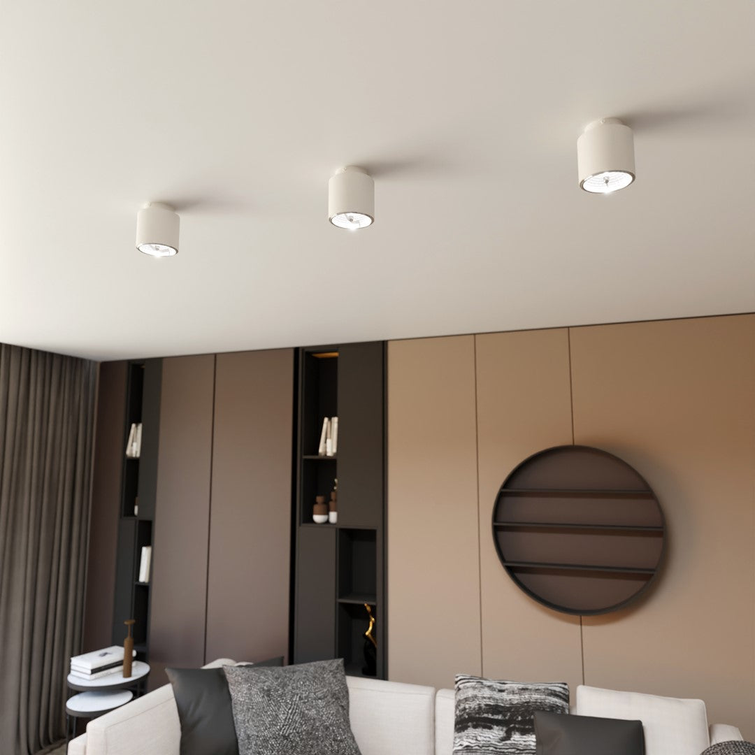 Trois plafonniers alignés au plafond d'un salon meublé, en situation d'ambiance.