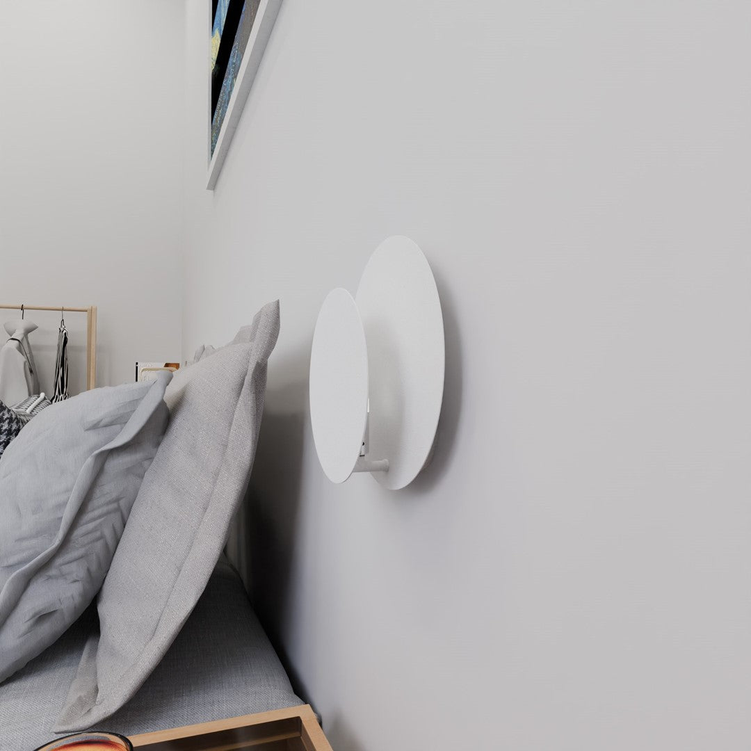 Vue rapprochée de l'applique murale blanche installée au-dessus de la tête de lit.
