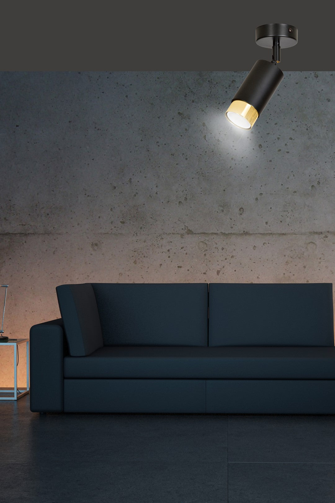 Mise en ambiance salon, spot orienté vers un mur béton au-dessus du canapé