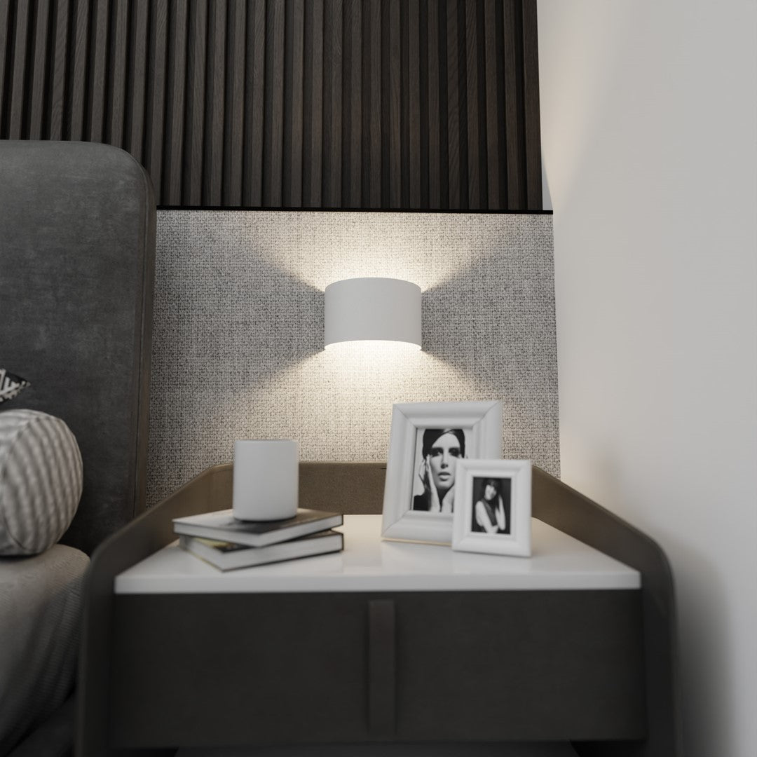 Ambiance nuit, halo lumineux projeté sur le papier peint texturé derrière le lit