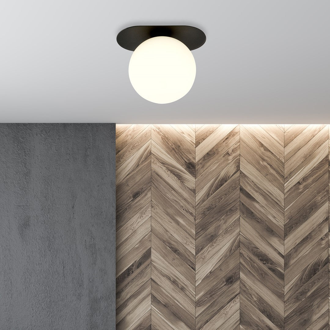 Plafonnier allumé dans un décor de parquet chevrons et béton gris