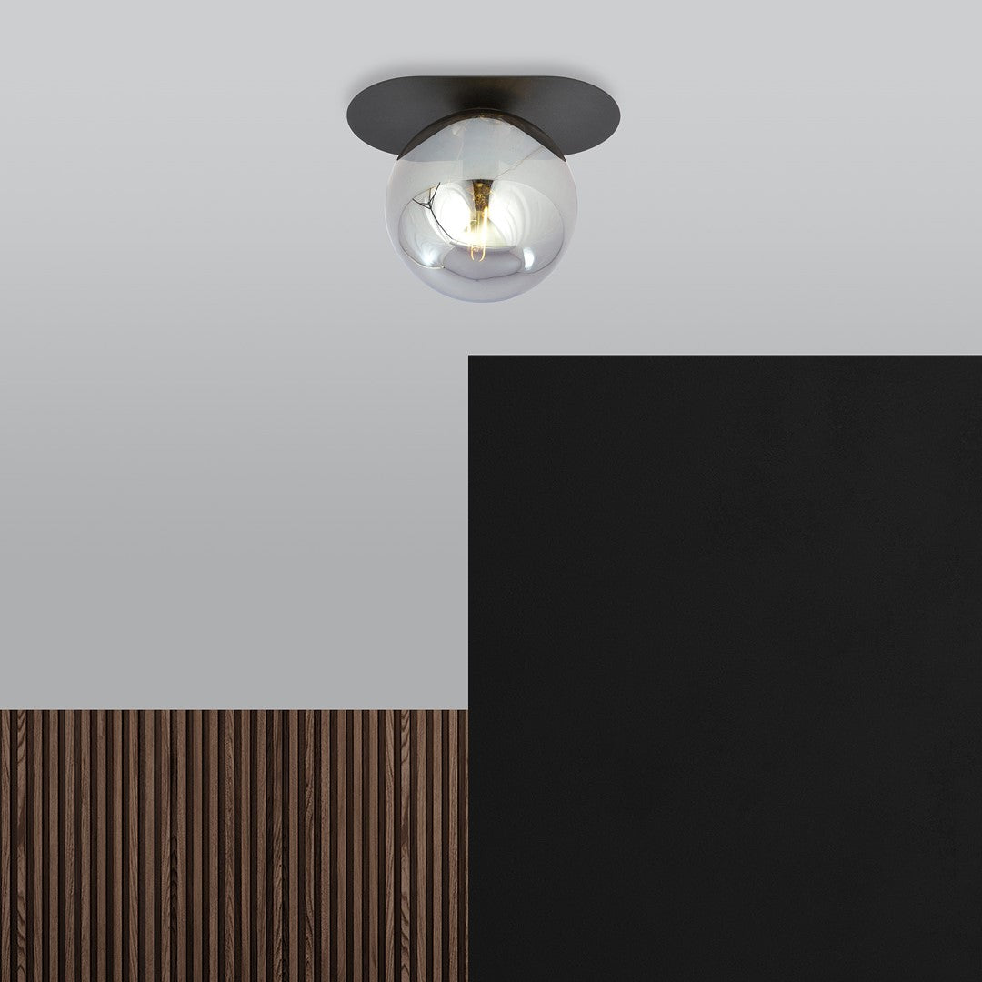Plafonnier allumé dans un décor contemporain, mur noir et tasseaux de bois.