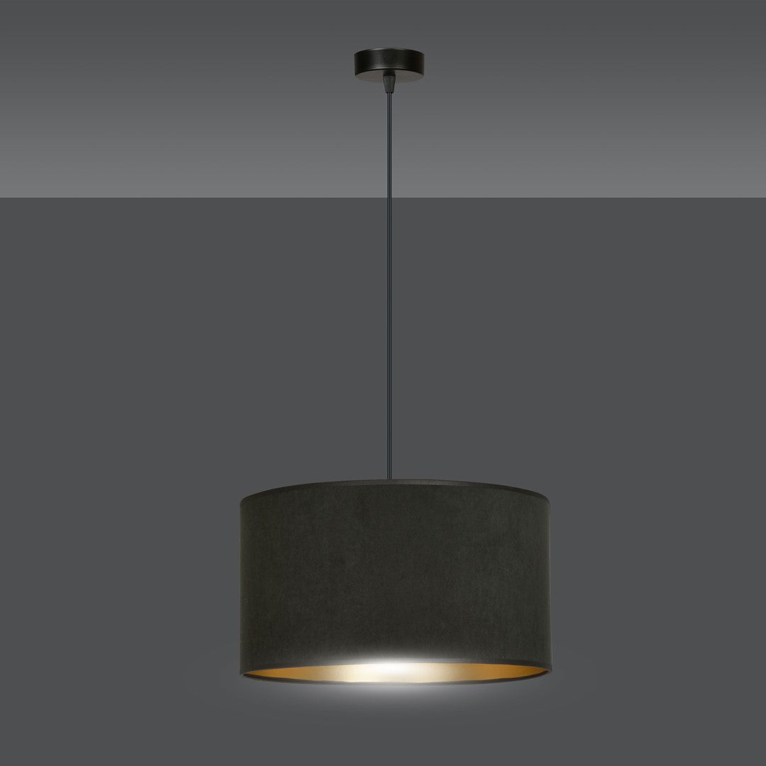 Suspension noire allumée sur fond gris, lumière chaude diffusée par l'intérieur doré.