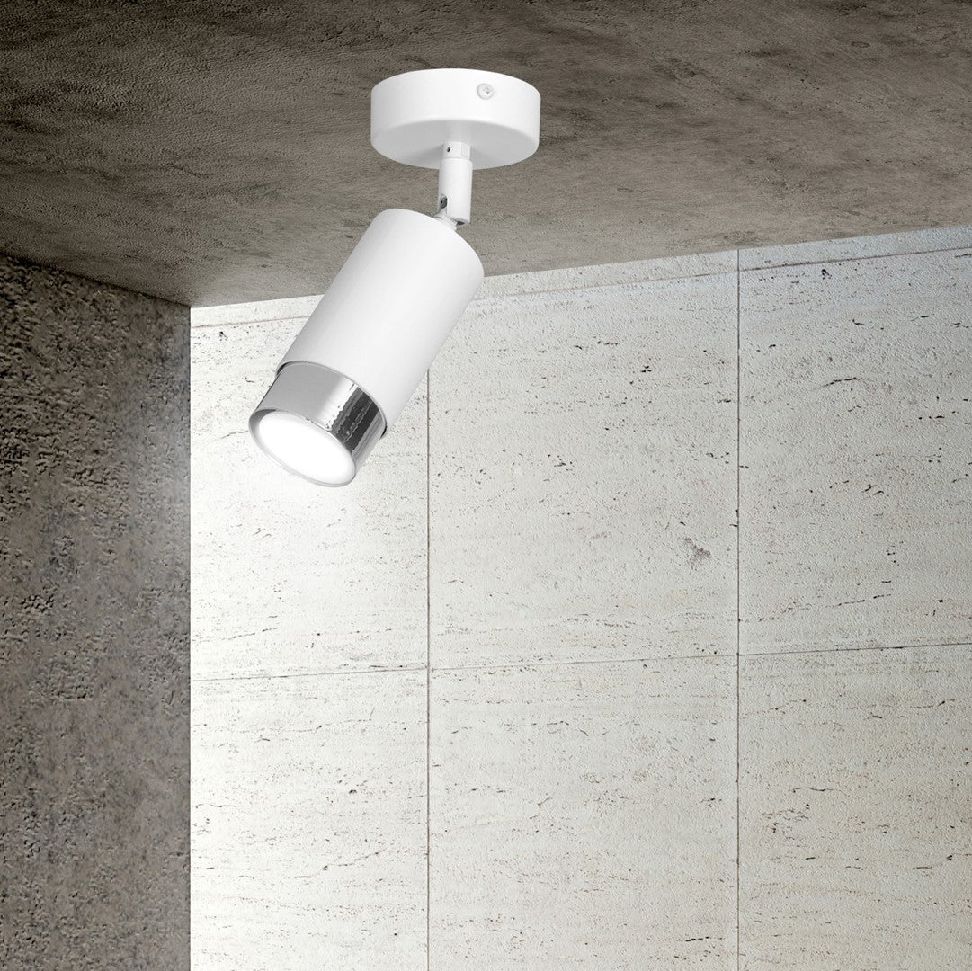 Vue rapprochée du spot au plafond, mur de béton clair et ombre portée