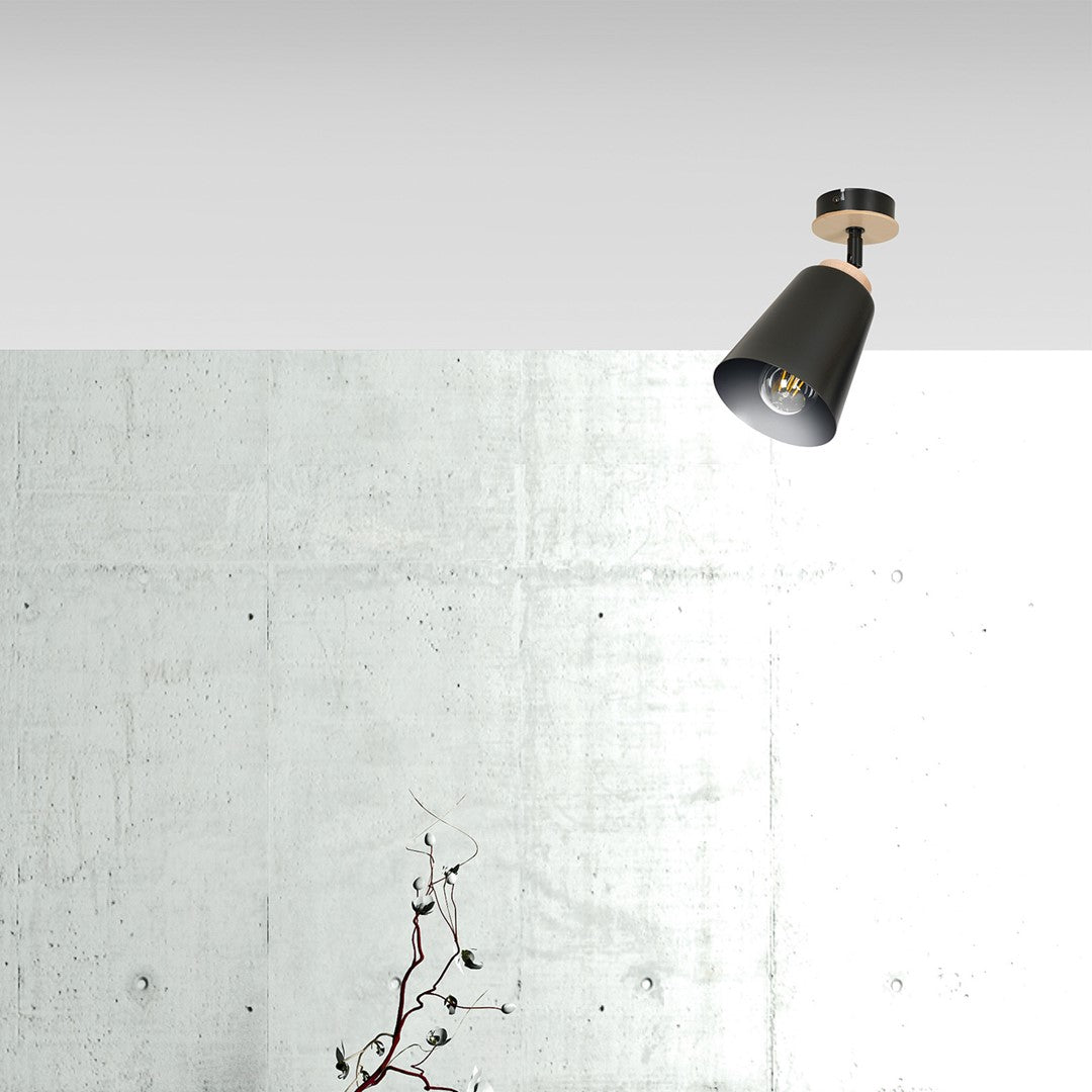 Gros plan du spot fixé au plafond devant un mur de béton brut