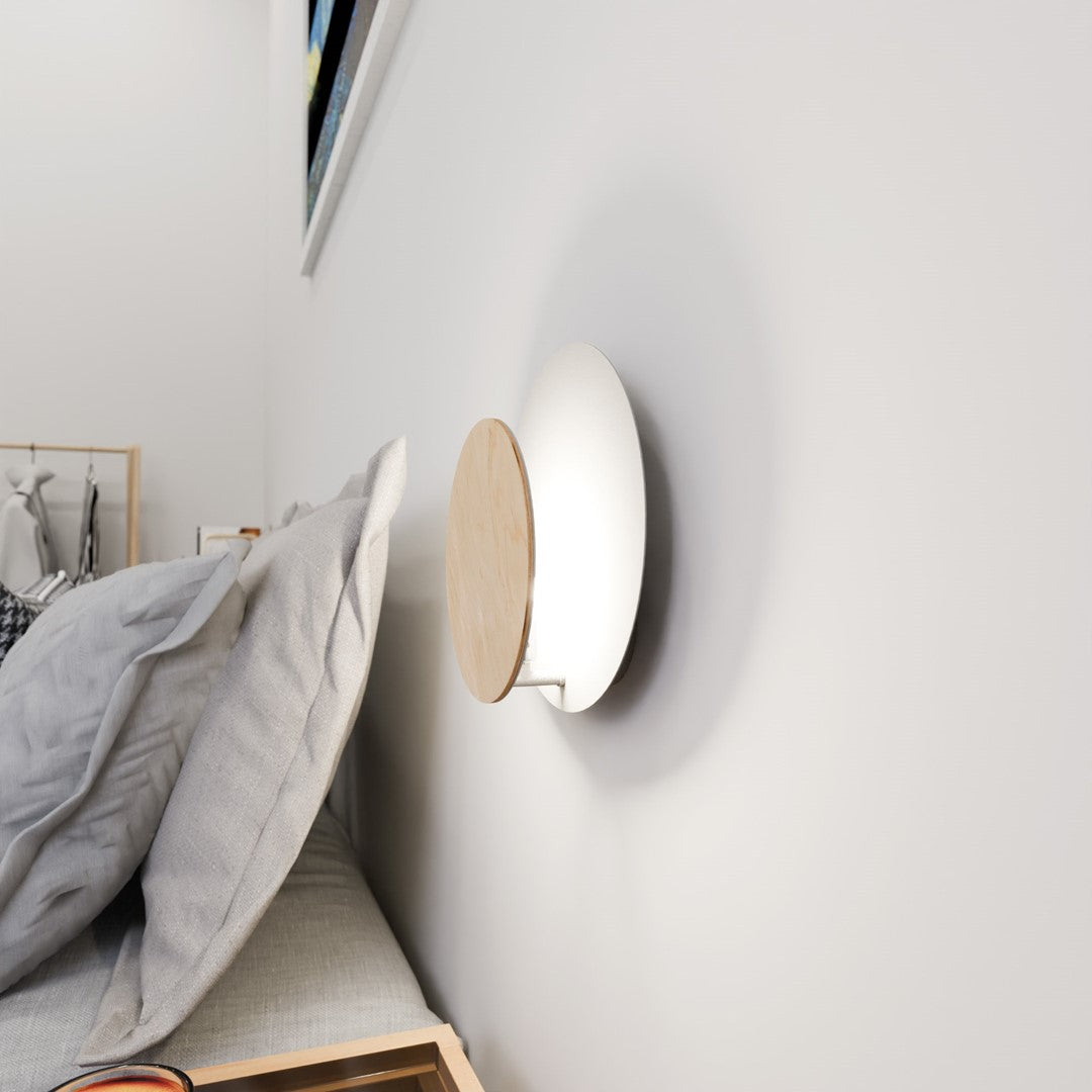 Vue de trois quarts en légère contre-plongée, disque bois incliné sur support mural blanc.