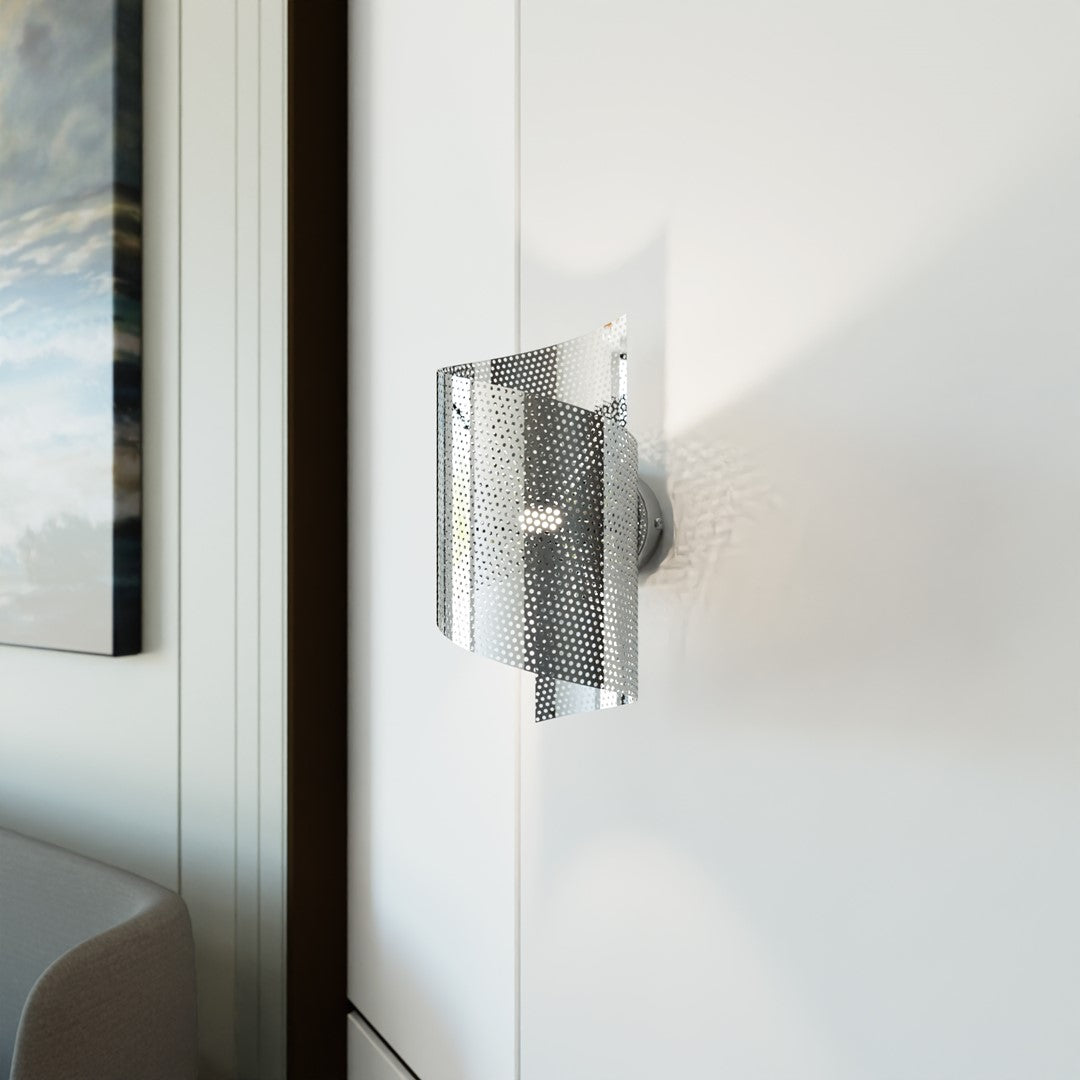 Gros plan du luminaire allumé, reflets sur le métal perforé et ombres portées