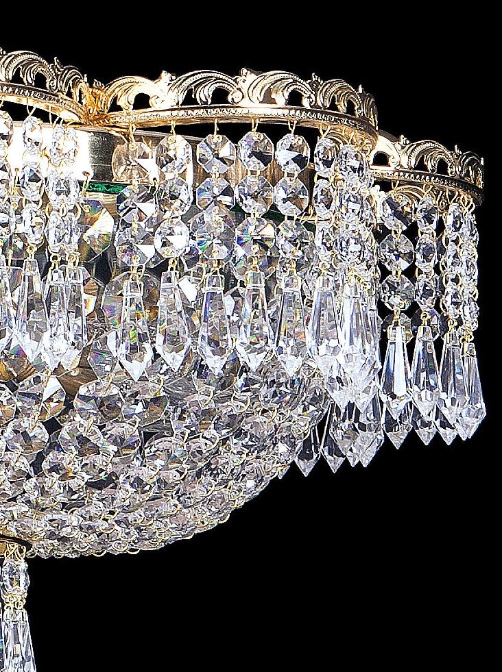 Vue rapprochée des gouttes de cristal facettées et de leur monture dorée.