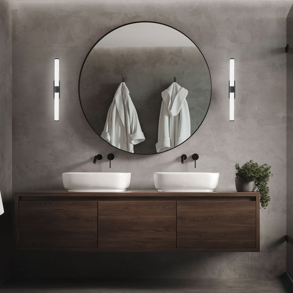 Deux appliques murales verticales encadrent un miroir rond dans une salle de bain.