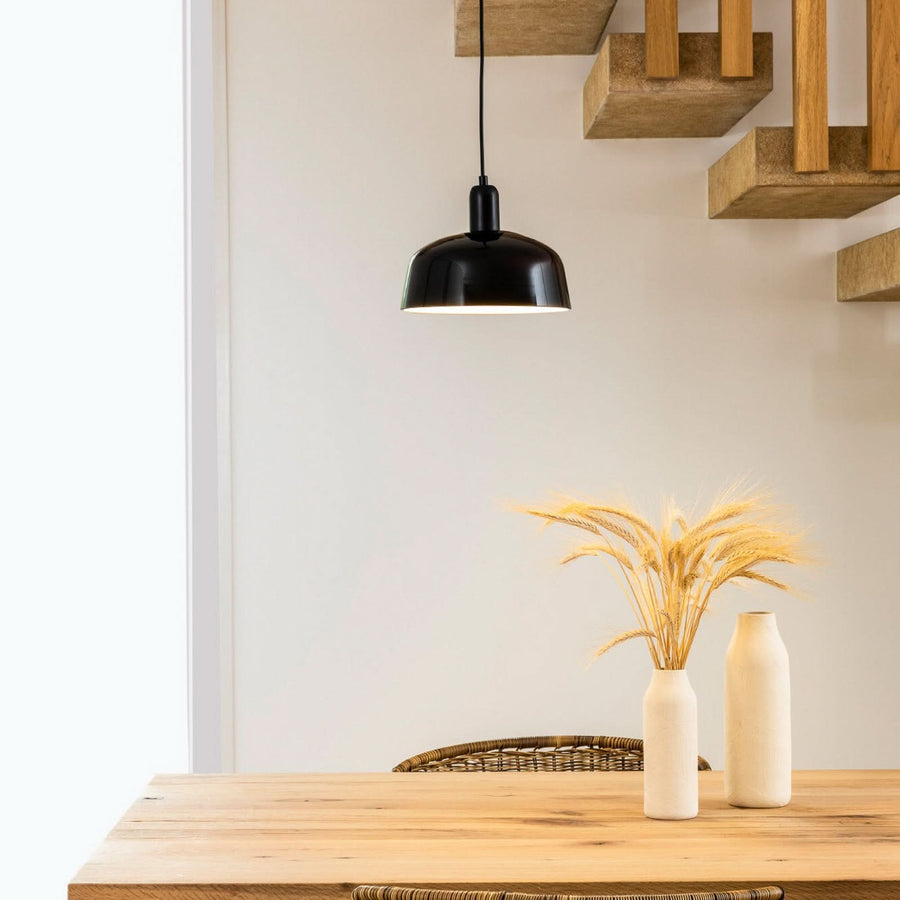 Suspension noire suspendue au-dessus d'une table en bois avec épis de blé.