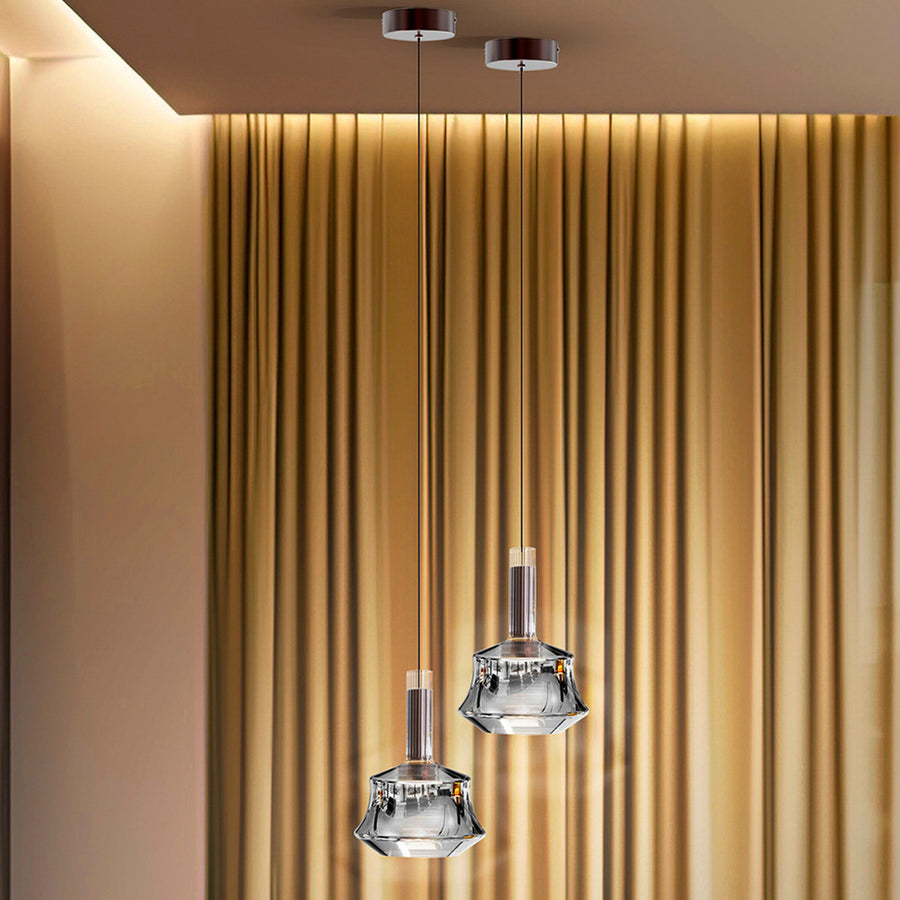 Gros plan sur deux suspensions en verre transparent aux détails métalliques bronze brossé.