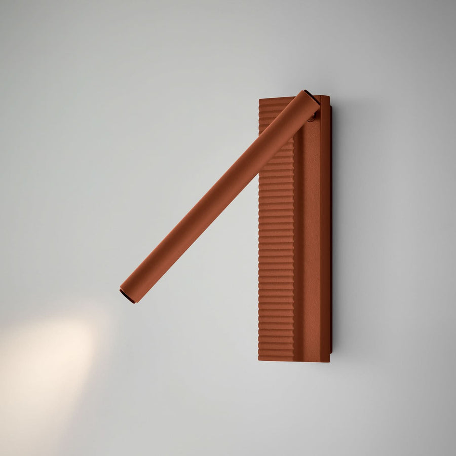 Applique terracotta installée sur mur gris clair, éclairage diffus vers le bas.