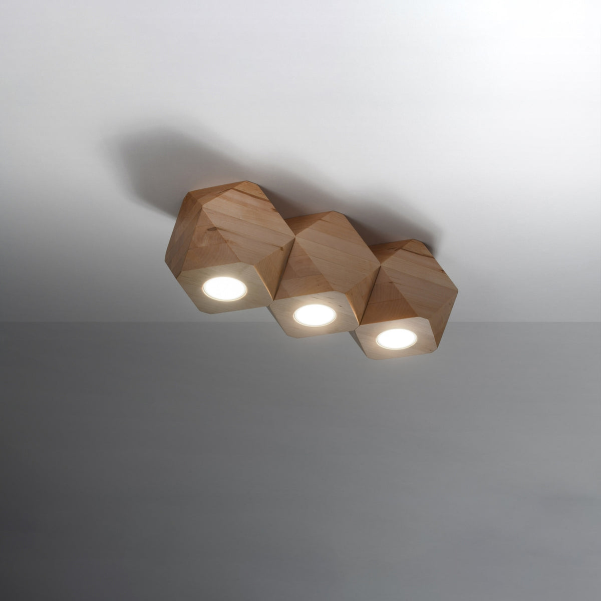 Luminaire allumé dans une pièce sombre, cônes de lumière projetés vers le bas.