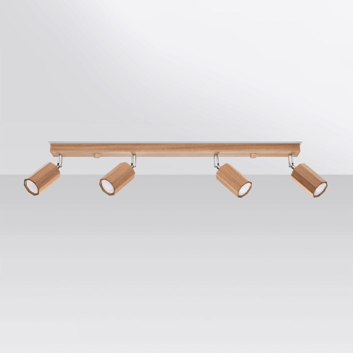 Plafonnier fixé au plafond blanc, quatre spots cylindriques en bois inclinés.