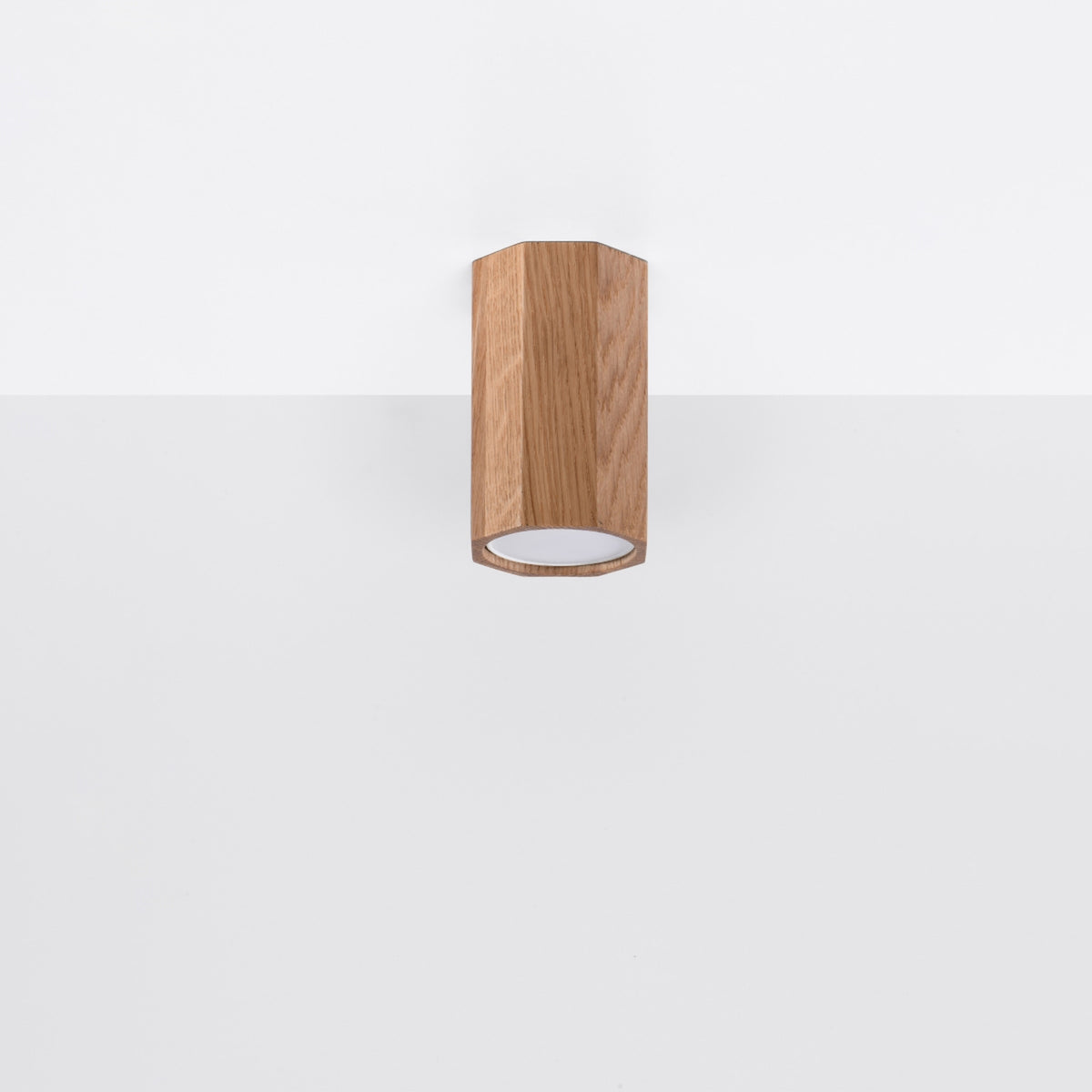 Luminaire installé verticalement sur une paroi blanche, éclairé légèrement.
