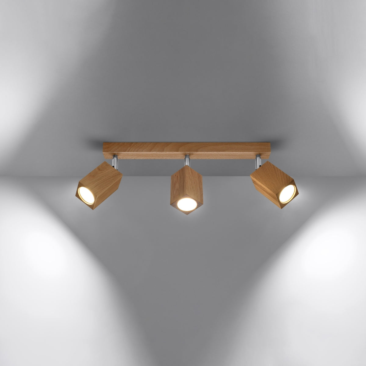 Luminaire allumé, trois faisceaux lumineux orientables éclairant une surface grise