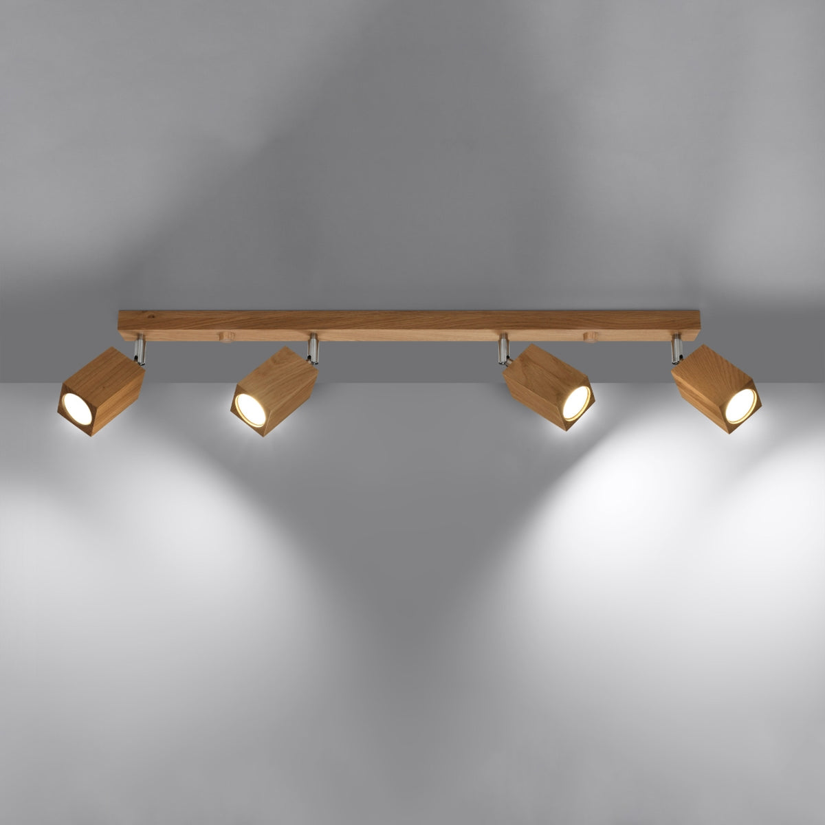 Plafonnier allumé projetant quatre faisceaux lumineux ronds sur un mur gris