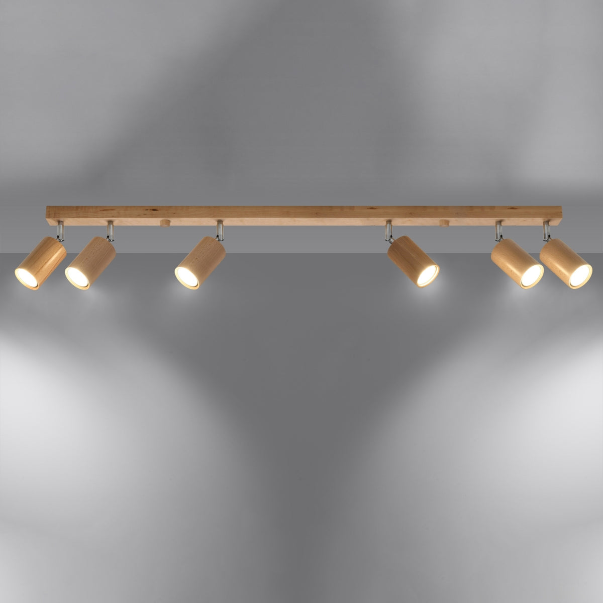 Luminaire allumé projetant six faisceaux lumineux sur une paroi grise.