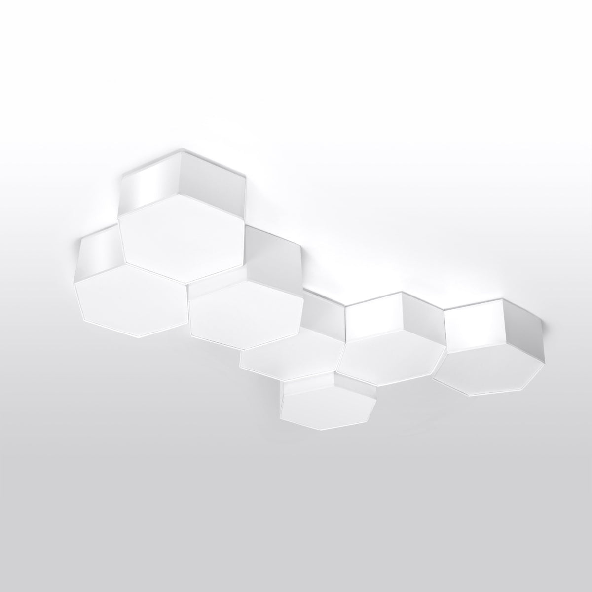 Composition hexagonale multiple installée au plafond dans une pièce blanche