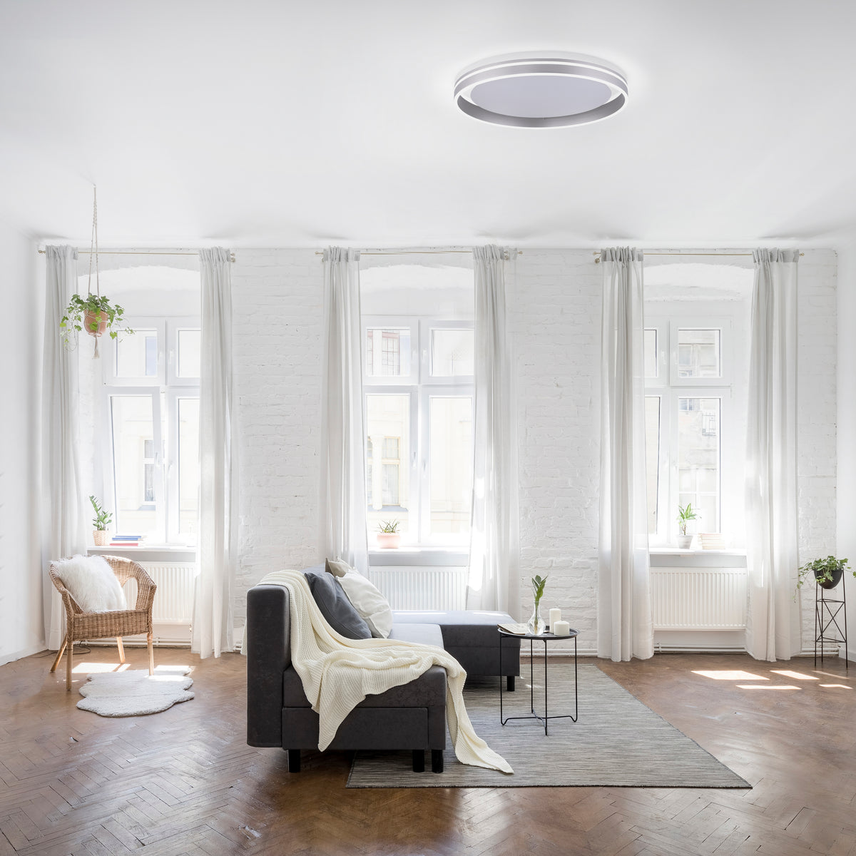 Plafonnier installé au plafond dans un séjour blanc lumineux avec canapé gris