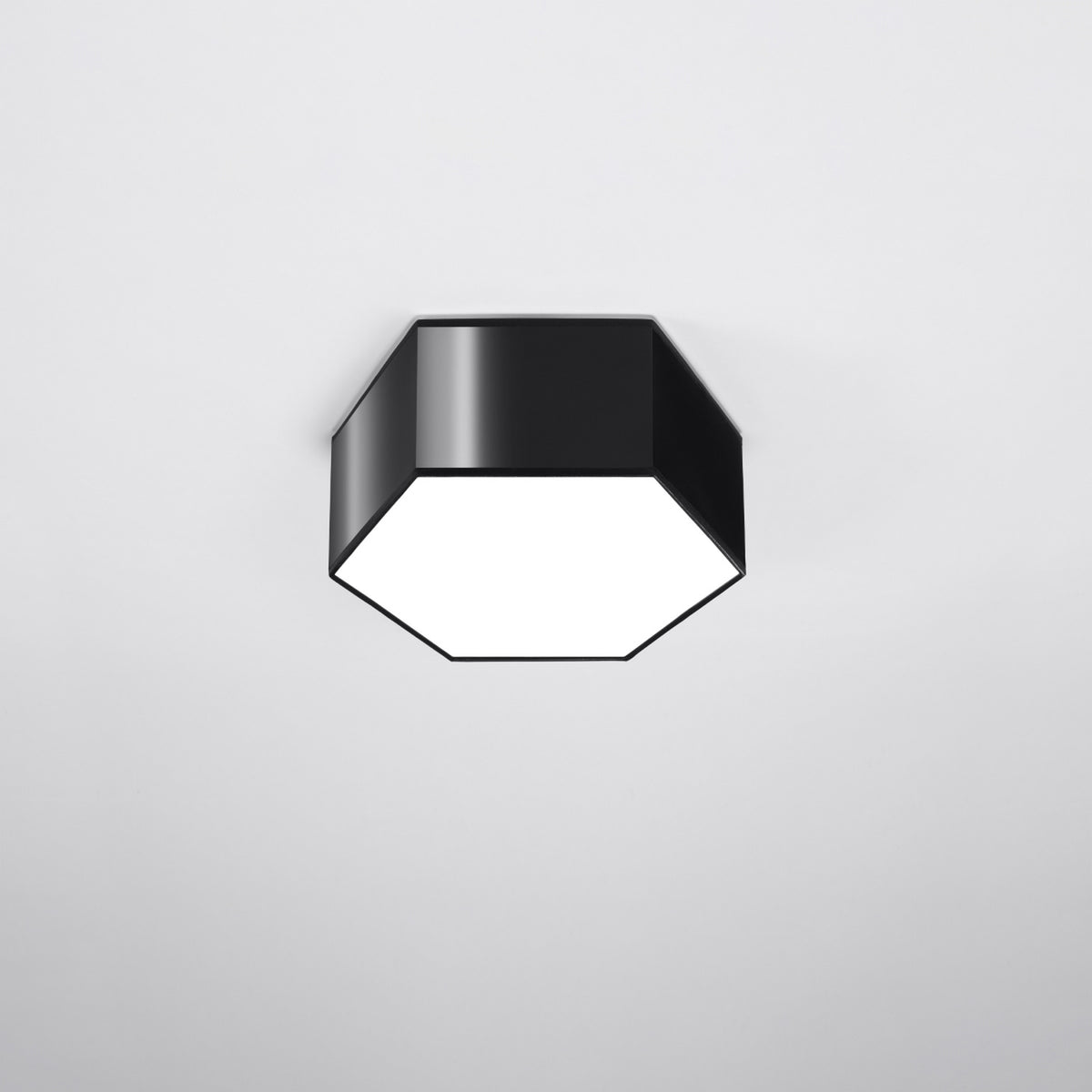Plafonnier hexagonal noir allumé, fixé au plafond dans une pièce claire
