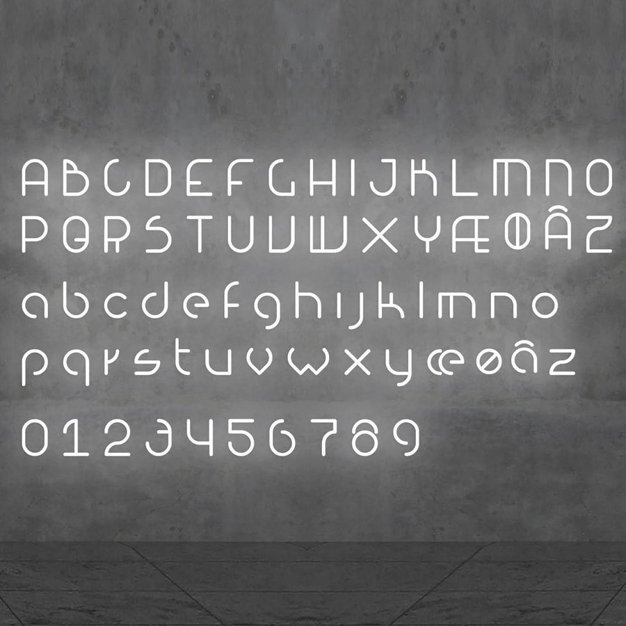 Alphabet complet lumineux en lettres blanches, chiffres inclus, sur un mur béton gris.